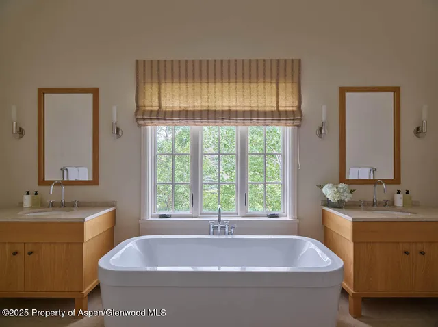 a bathroom with a tub a sink and a window