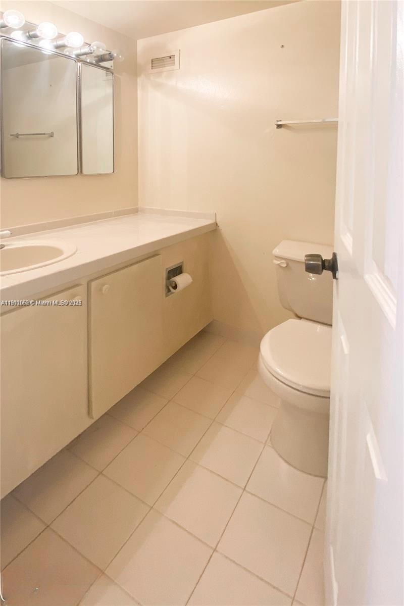 430 Golden Isles Drive, Unit 701 Hallandale Beach, FL 33009 - Photo 6 of 11 a bathroom with a toilet a sink and mirror