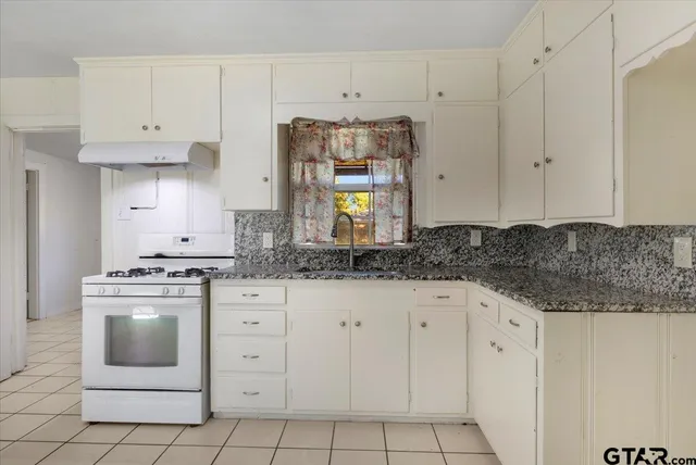a kitchen with granite countertop white cabinets and white appliances