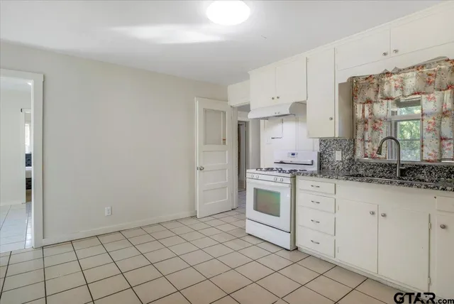 a kitchen with granite countertop white cabinets and white appliances