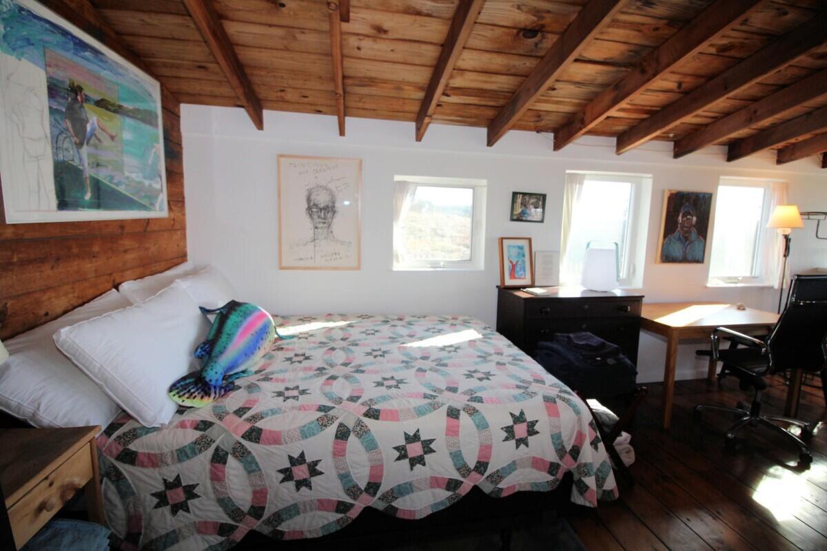 75 Richman Lane Wellfleet, MA 02667 - Photo 56 of 72 a bedroom with a bed a table and chair with wooden floor