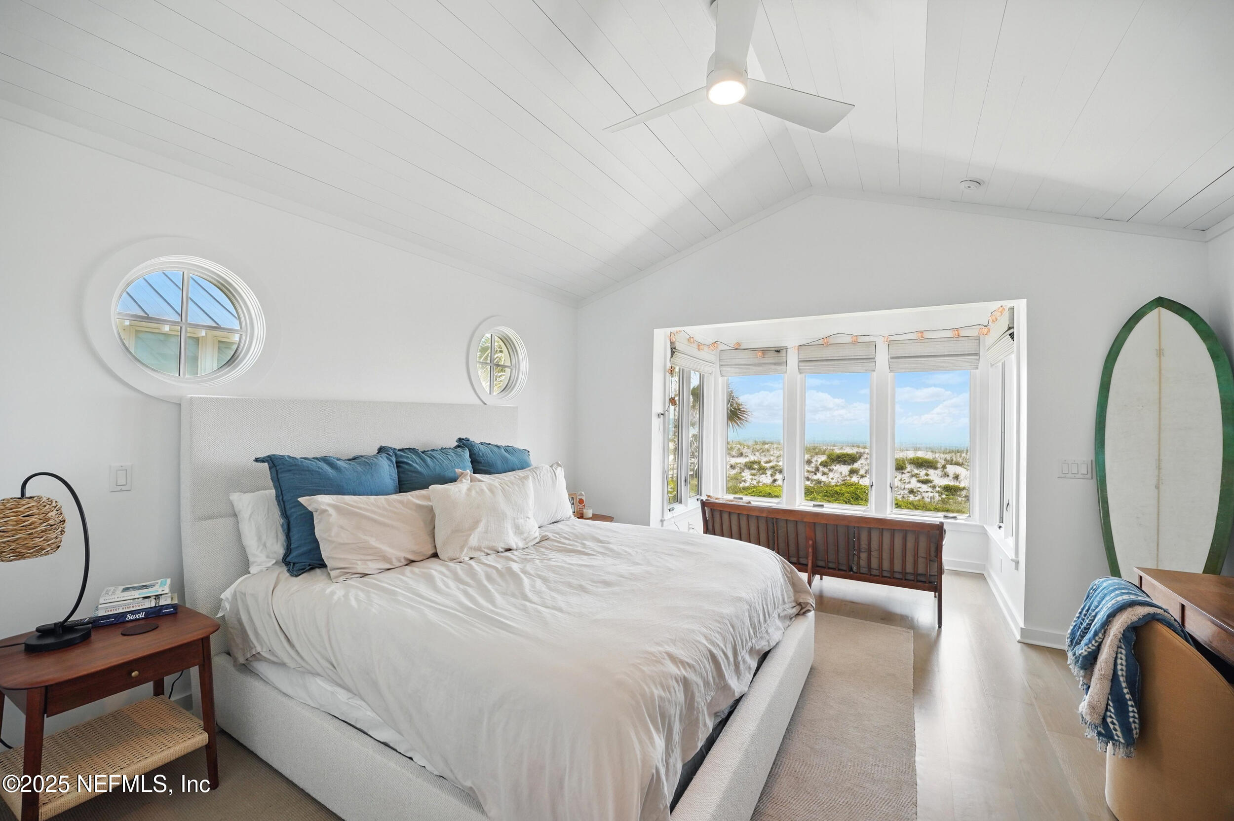 816 Ocean Front Neptune Beach, FL 32266 - Photo 26 of 65 a bedroom with a bed a mirror on dresser and a large window