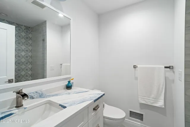 a bathroom with a granite countertop sink toilet a mirror and shower