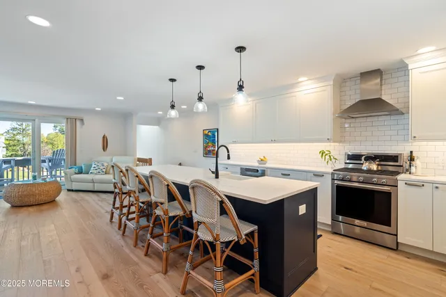 a kitchen with stainless steel appliances granite countertop a sink a stove and a wooden floors