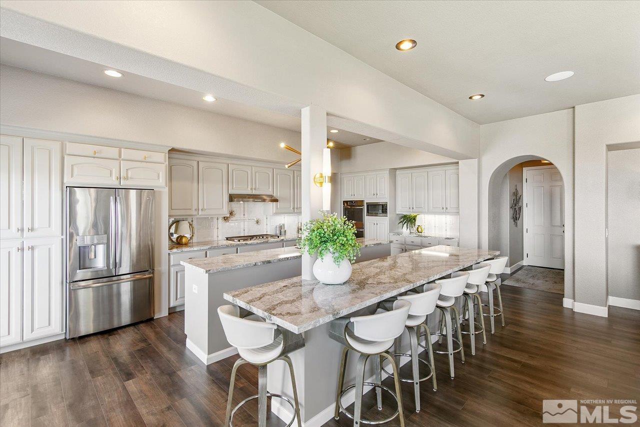 2956 Flint Ridge Court Reno, NV 89511 - Photo 22 of 40 a kitchen with stainless steel appliances granite countertop a dining table chairs refrigerator and cabinets