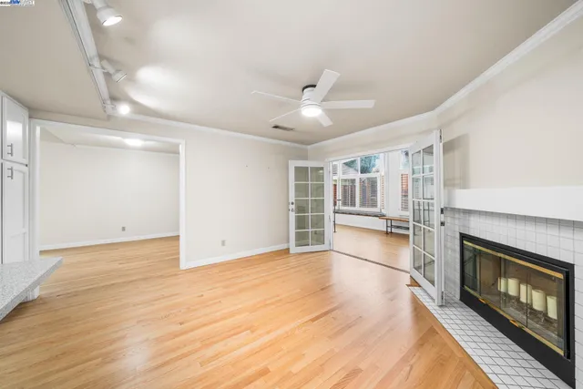 a view of an empty room with a fireplace and a ceiling fan