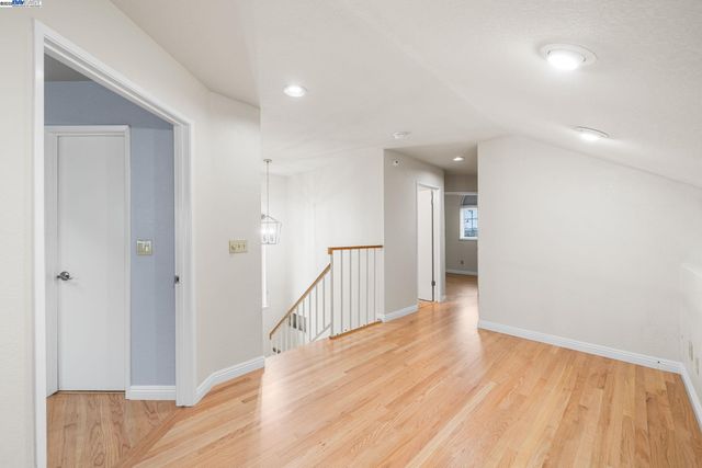 a view of a hallway with wooden floor and a bathroom