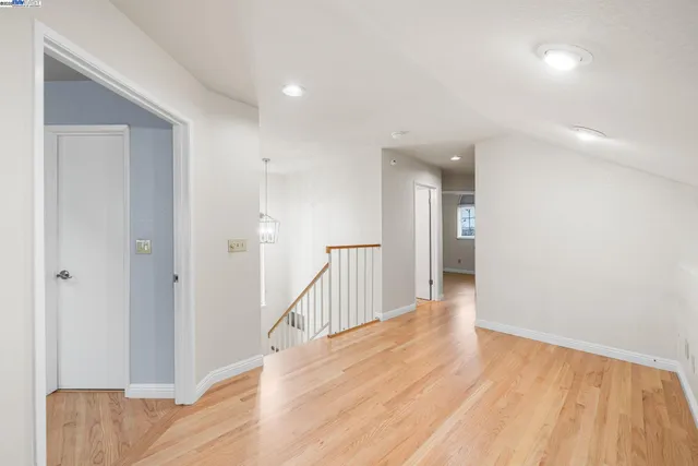 a view of a hallway with wooden floor and a bathroom