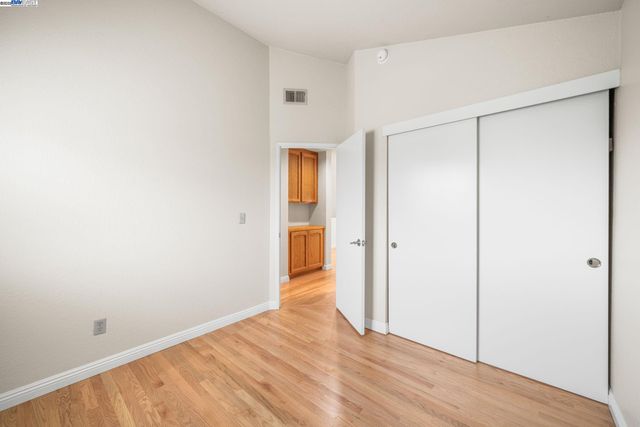 a view of an empty room with wooden floor and a bathroom
