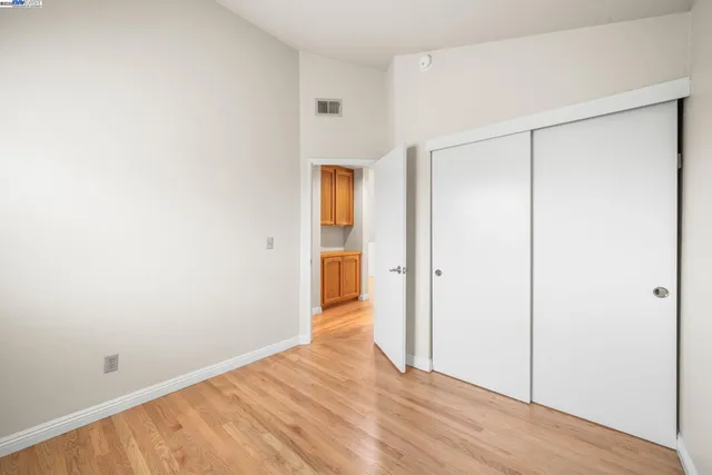 a view of an empty room with wooden floor and a bathroom