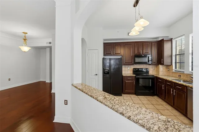 a kitchen with stainless steel appliances granite countertop a refrigerator a sink dishwasher a stove with wooden cabinets and floor