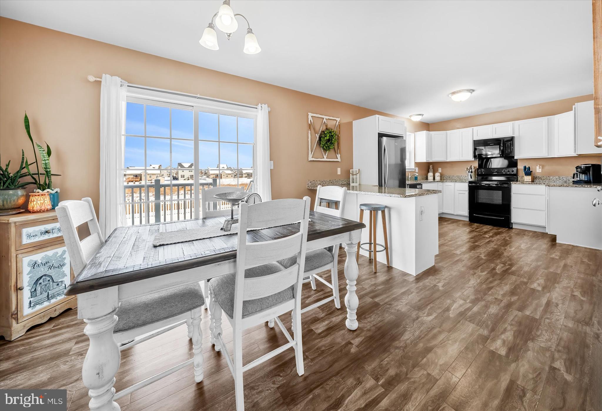 312 Doylestown Road Smyrna, DE 19977 - Photo 11 of 36 a kitchen with stainless steel appliances kitchen island granite countertop a stove a refrigerator a sink a dining table and chairs with wooden floor