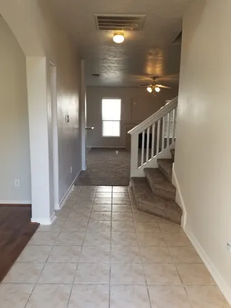 an empty room with wooden floor chandelier and windows