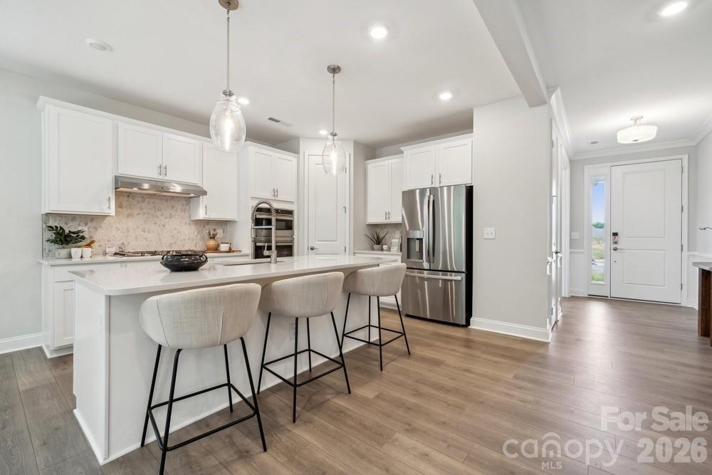 5041 Duval Circle Tega Cay, SC 29708 - Photo 11 of 47 a kitchen with stainless steel appliances granite countertop a refrigerator a oven a sink a stove a dining table and chairs with wooden floor