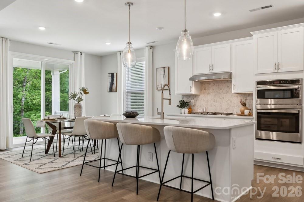 5041 Duval Circle Tega Cay, SC 29708 - Photo 13 of 47 a kitchen with stainless steel appliances granite countertop a stove a sink a kitchen island with chairs and wooden floor