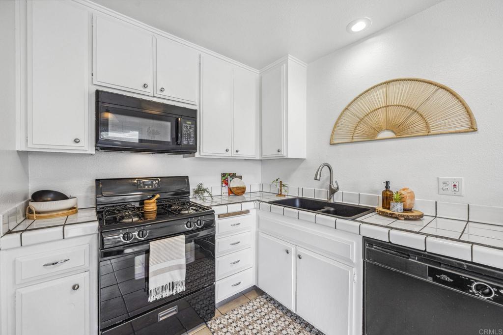3431 Seabreeze Walk Oceanside, CA 92056 - Photo 13 of 23 a kitchen with stainless steel appliances granite countertop a stove a sink dishwasher and a microwave oven with white cabinets