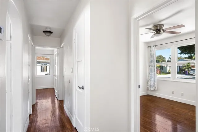 a view of a hallway with wooden floor and a bathroom
