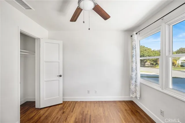 a view of empty room with wooden floor and fan