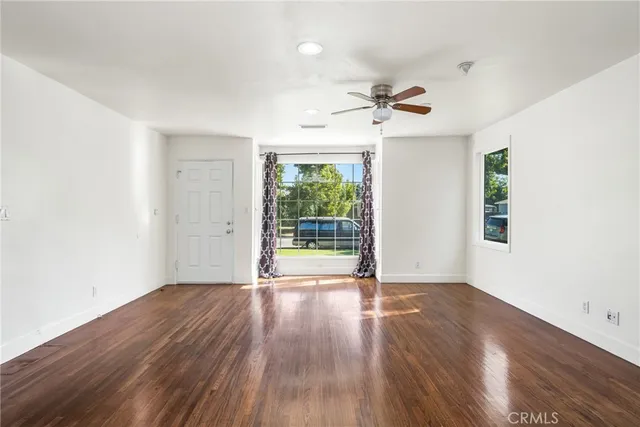 a view of a room with wooden floor ceiling fan and window