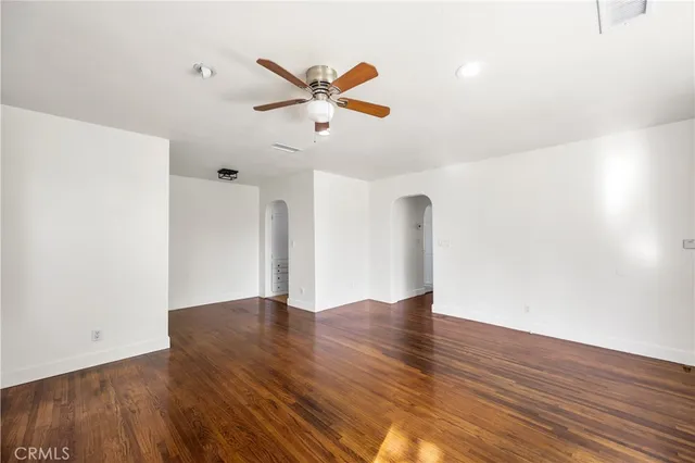 a view of empty room with wooden floor and ceiling fan
