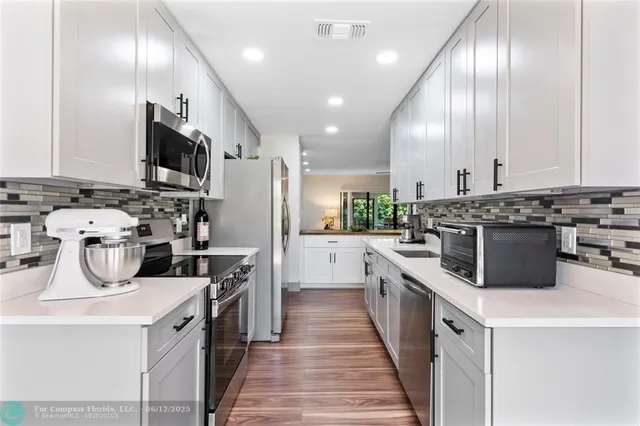 a kitchen with kitchen island stainless steel appliances a sink a stove top oven a counter space and cabinets