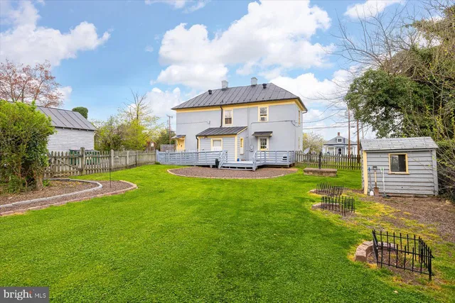 a view of a house with a big yard potted plants and large tree