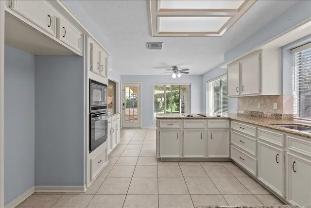 a large white kitchen with cabinets and a window