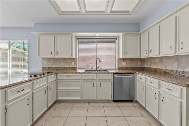 a kitchen with white cabinets appliances a sink and a window