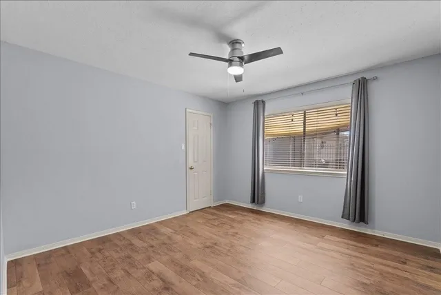 a view of a big room with windows and ceiling fan