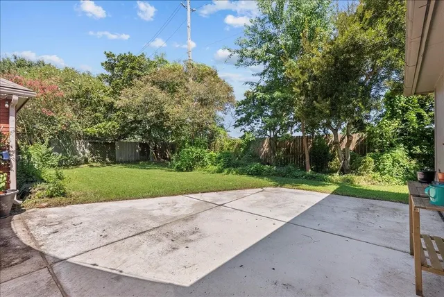 a view of a white house next to a yard with large trees