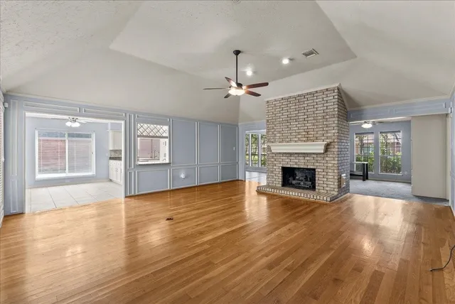 a view of an empty room with wooden floor fireplace and a window