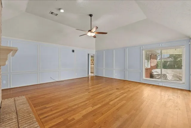 a view of empty room with wooden floor and fan