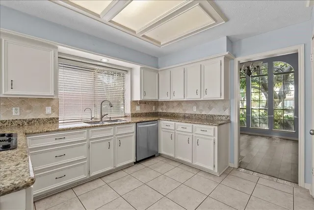 a kitchen with white cabinets and sink
