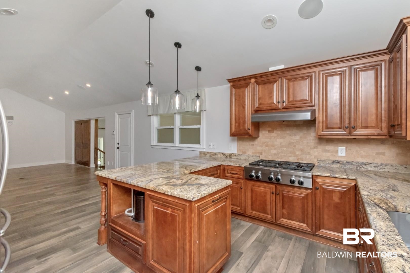 231 Rochester Road Mobile, AL 36608 - Photo 12 of 51 Kitchen with wood finish cabinetry, light stone countertops, a peninsula, lofted ceiling, and stainless steel gas stovetop