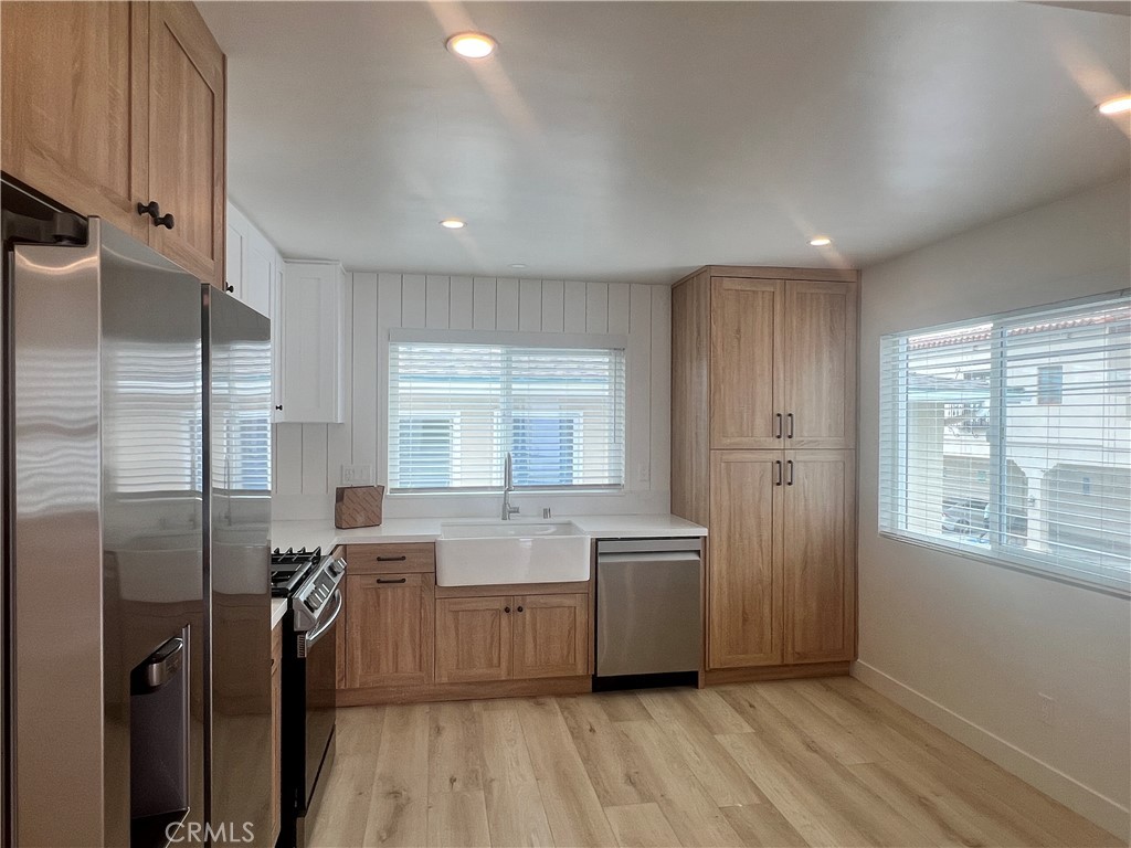 a kitchen with stainless steel appliances a sink a refrigerator and wooden floor