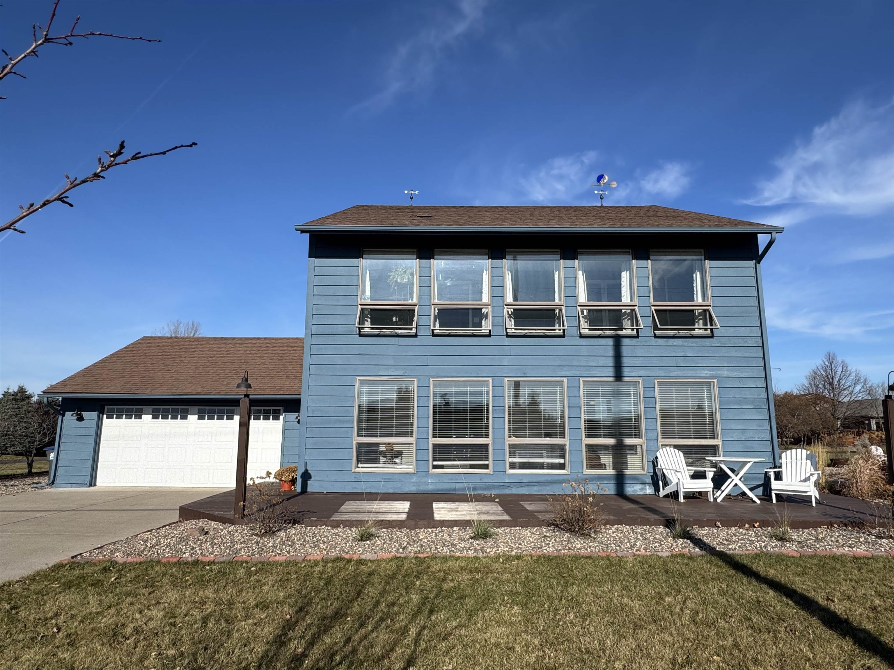 Back of property with a garage, concrete driveway, a lawn, and a shingled roof