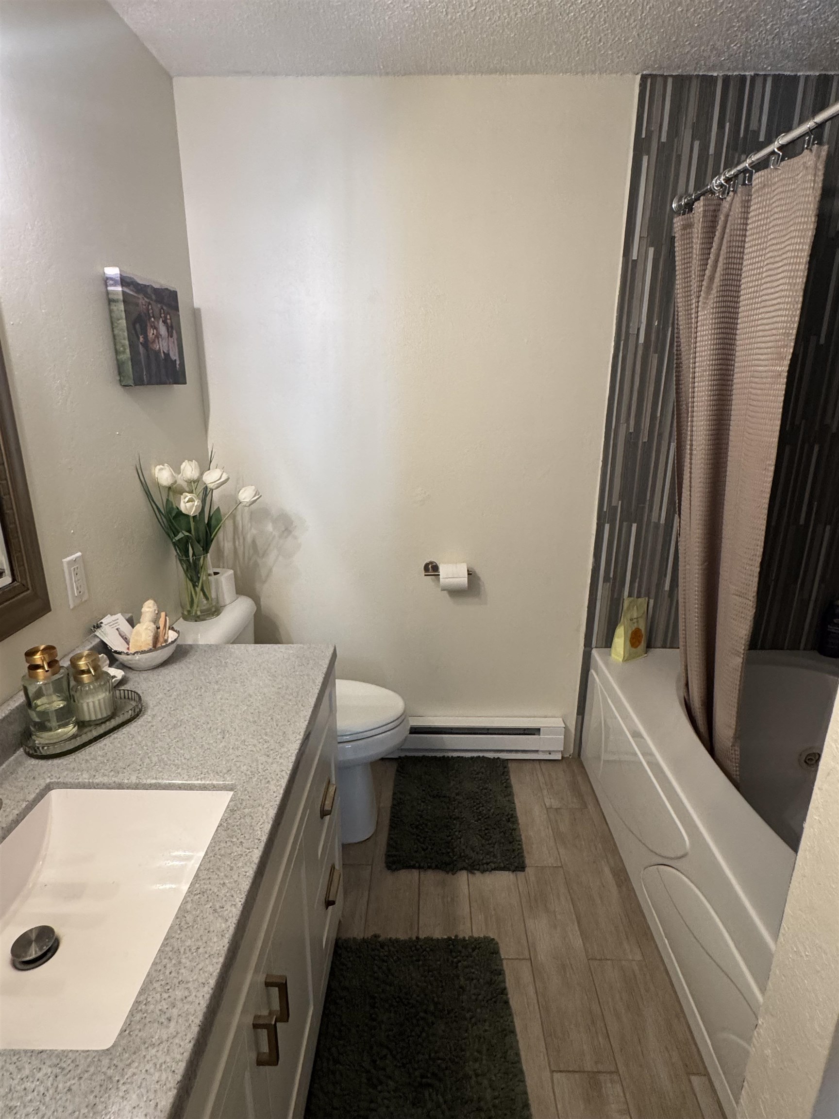 1217 North 33rd Street Superior, WI 54880 - Photo 15 of 21 Bathroom featuring vanity, light wood-style floors, shower / bath combination with curtain, a textured ceiling, and a baseboard heating unit
