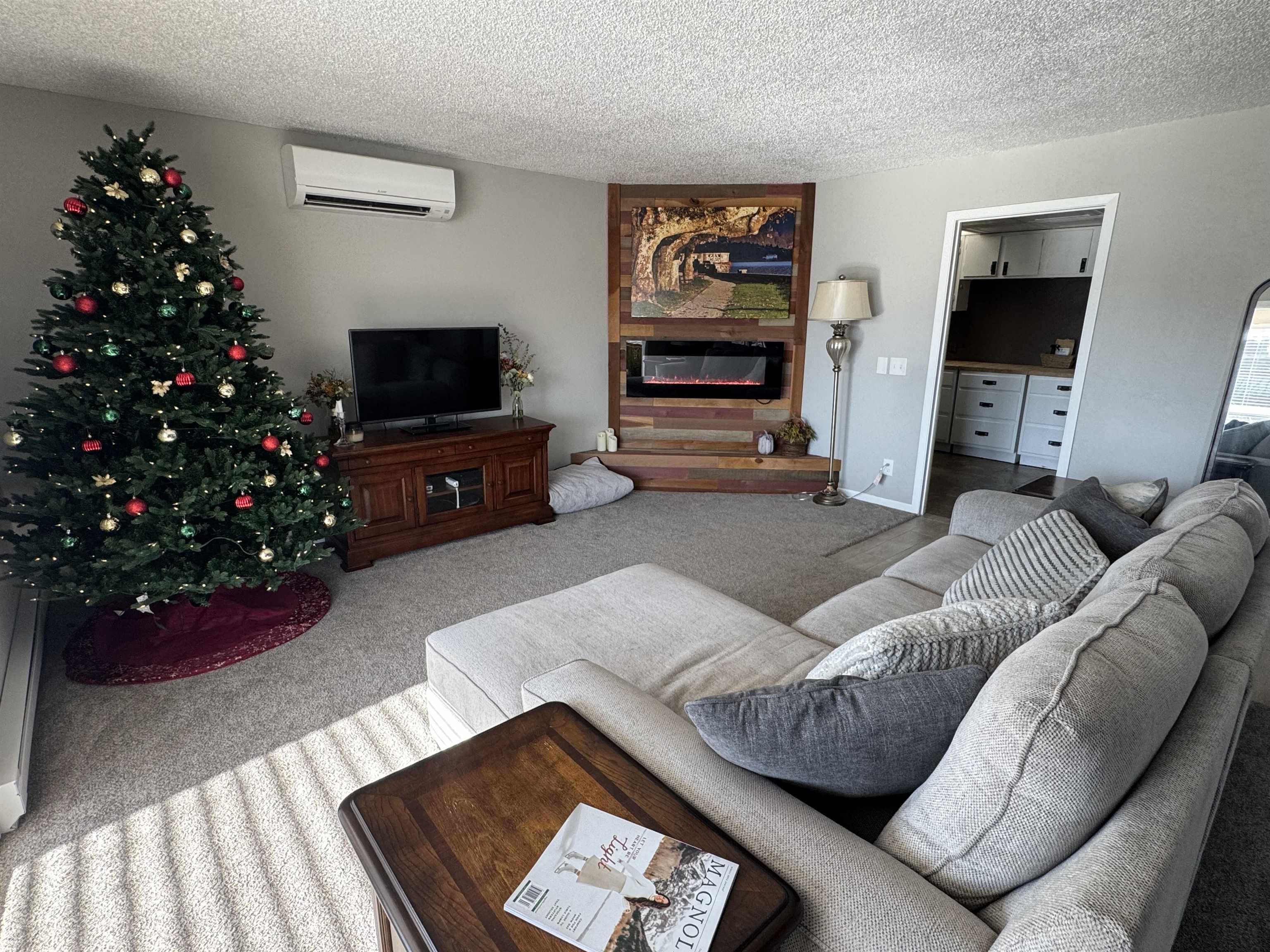 1217 North 33rd Street Superior, WI 54880 - Photo 3 of 21 Carpeted living area featuring a textured ceiling, a glass covered fireplace, and a wall unit AC