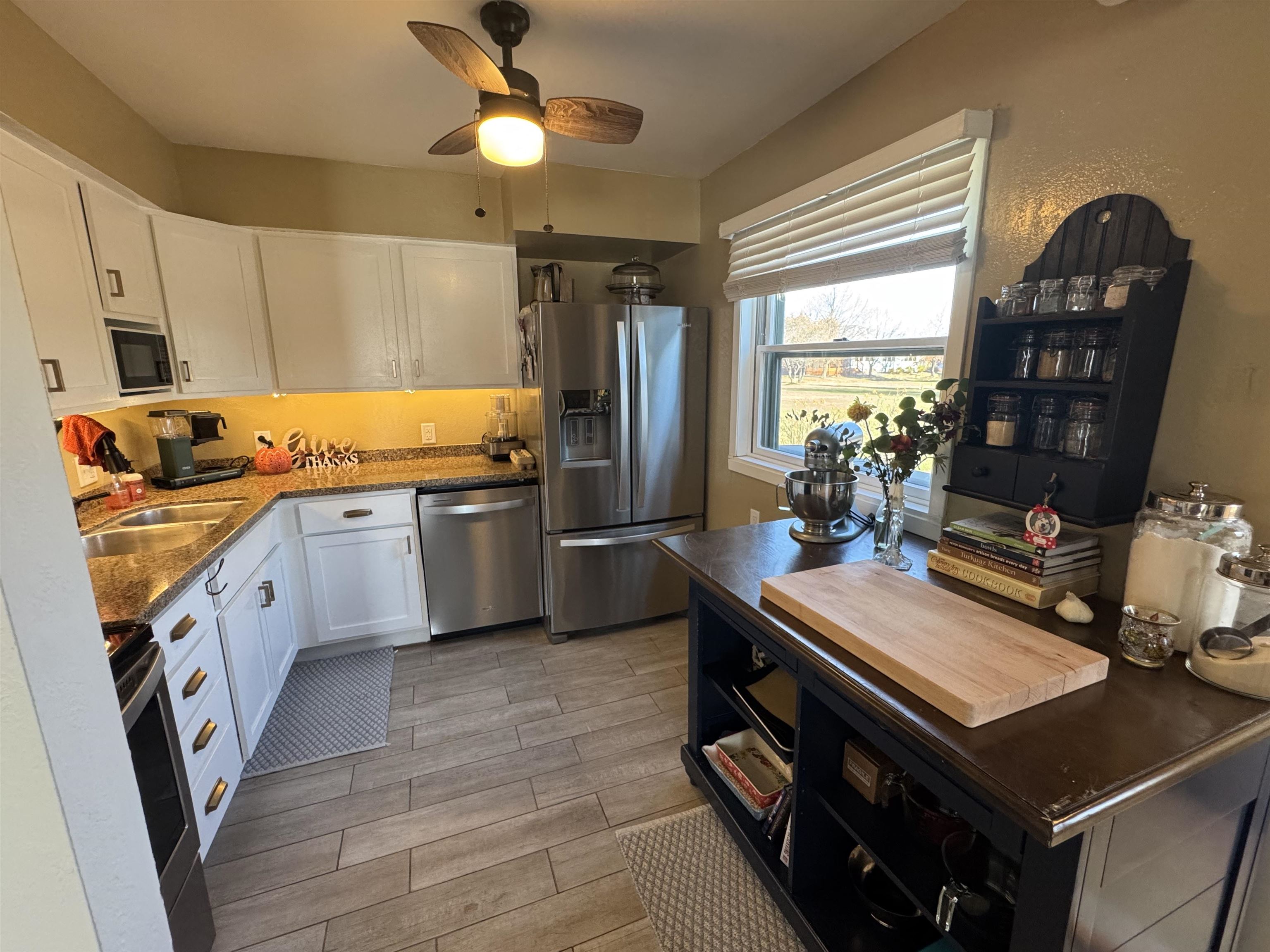 1217 North 33rd Street Superior, WI 54880 - Photo 8 of 21 Kitchen with white cabinets, stainless steel appliances, wood finish floors, ceiling fan, and dark stone countertops