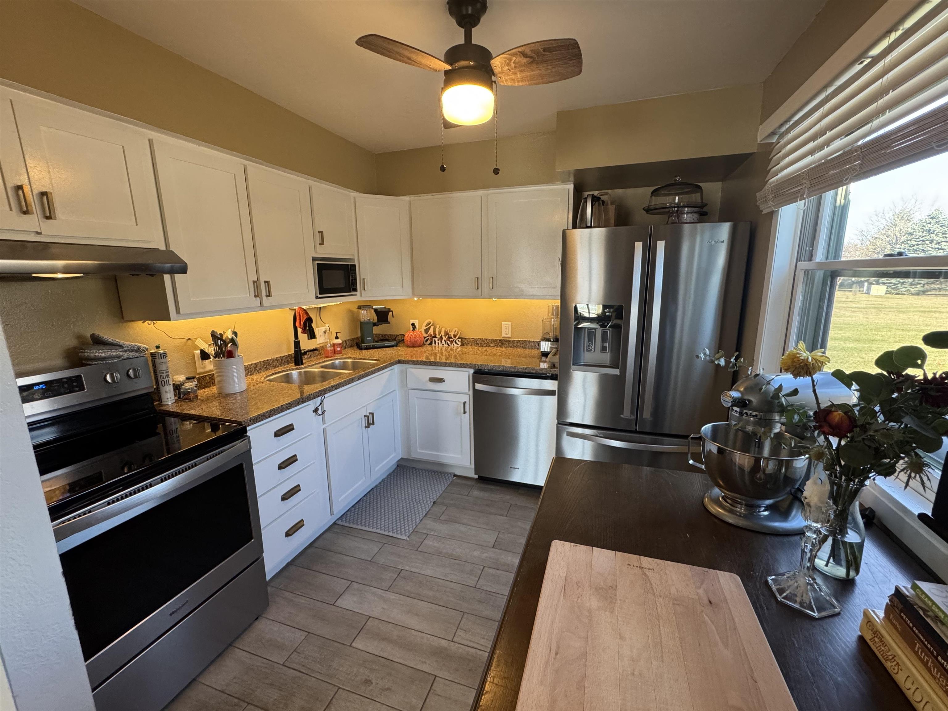 1217 North 33rd Street Superior, WI 54880 - Photo 9 of 21 Kitchen featuring appliances with stainless steel finishes, white cabinets, wood tiled floors, dark stone counters, and ceiling fan