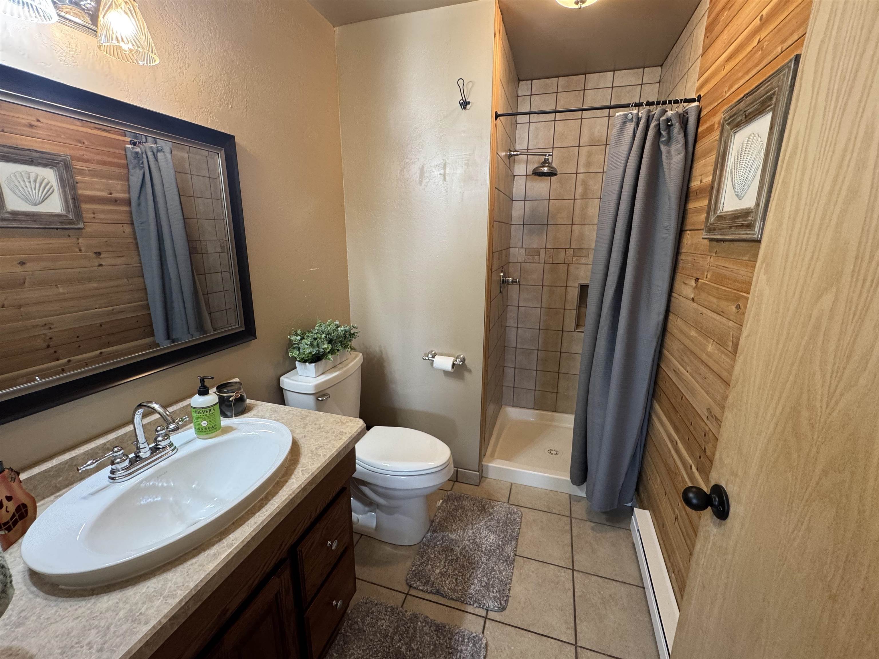 1217 North 33rd Street Superior, WI 54880 - Photo 10 of 21 Bathroom with vanity, a stall shower, a baseboard heating unit, and light tile patterned floors