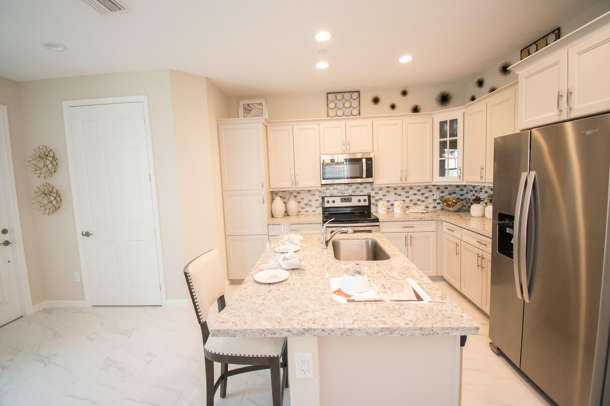 14426 Emerald Pl Way Delray Beach, FL 33484 - Photo 6 of 15 a kitchen with stainless steel appliances granite countertop a kitchen island a stove a refrigerator a sink a dining table and chairs