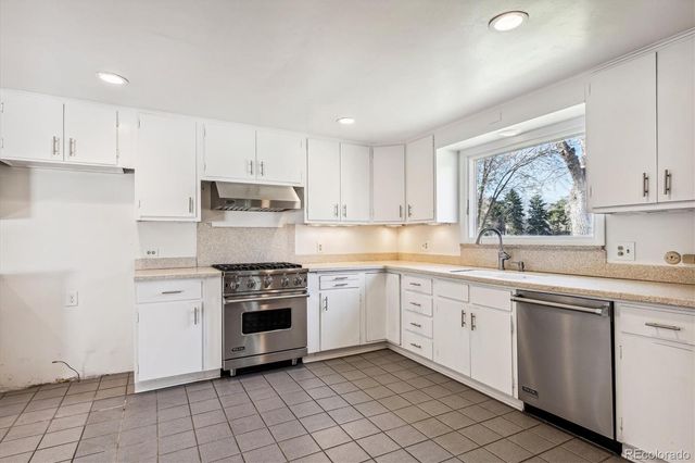 a kitchen with white cabinets appliances and a sink