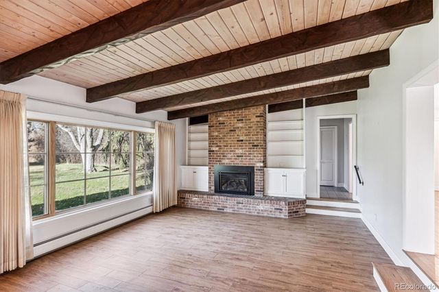 a view of a livingroom with wooden floor and a fireplace