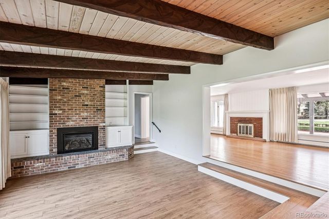 a view of an empty room with wooden floor fireplace and a window