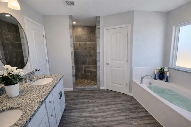 a bathroom with a granite countertop tub a sink and a shower