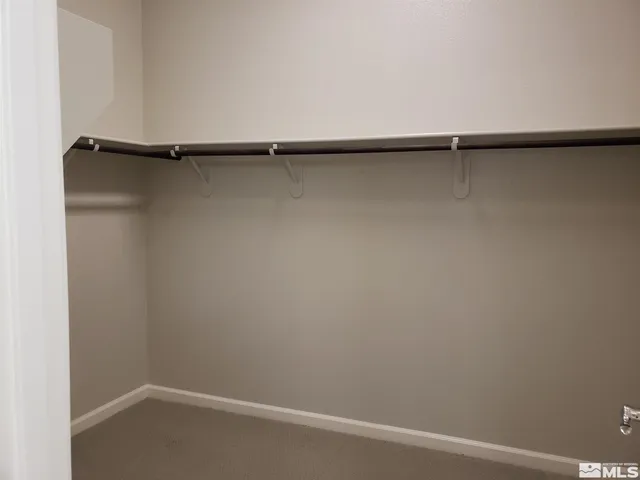 a view of an empty room with closet and a mirror