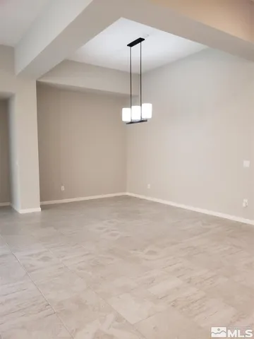 a view of an empty room with a chandelier fan