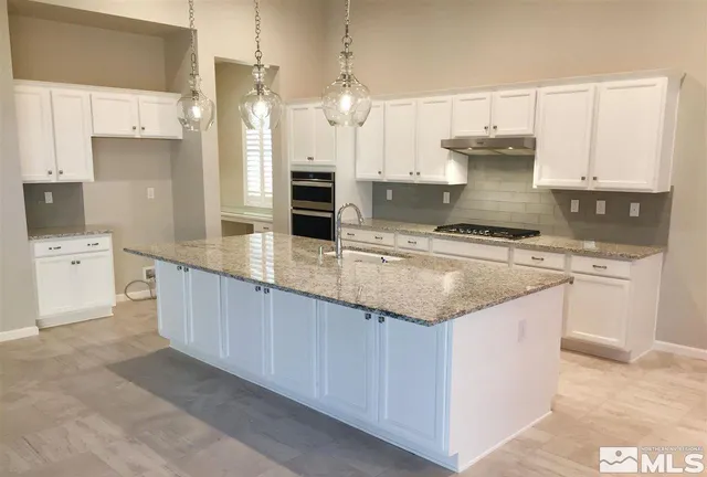 a kitchen with granite countertop a sink a counter top space appliances and cabinets