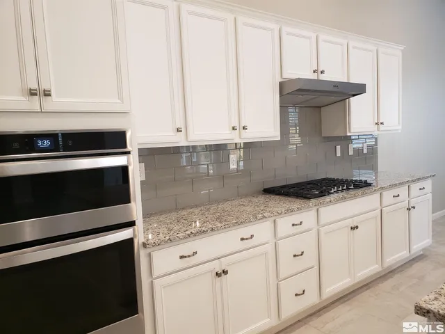 a kitchen with granite countertop white cabinets and a stove